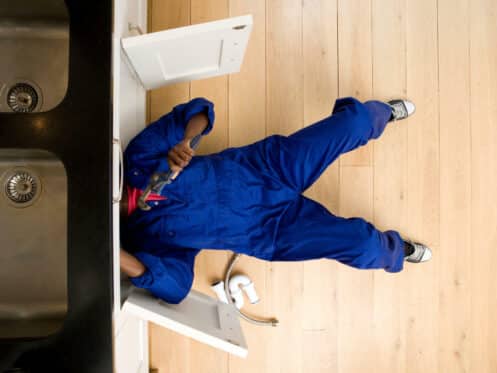 emergency-plumber-working-under-the-kitchen-sink