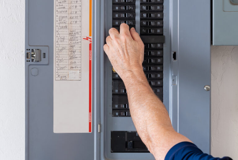 man fixing a tripped electrical breaker